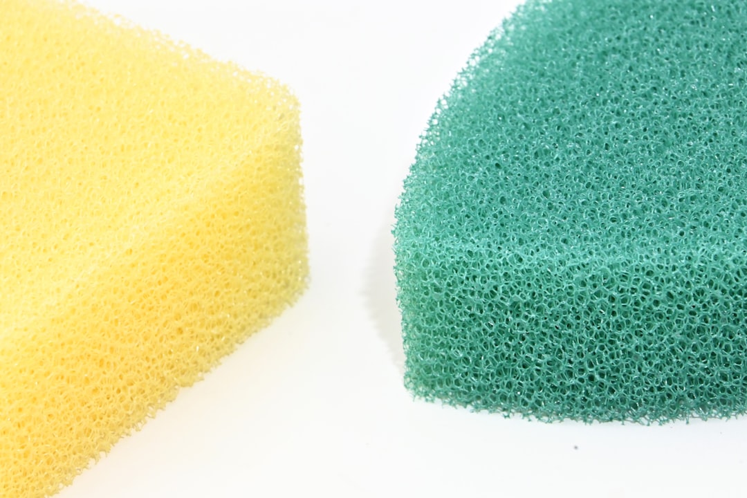 Yellow and green cleaning sponges shown in close-up against a clean white background