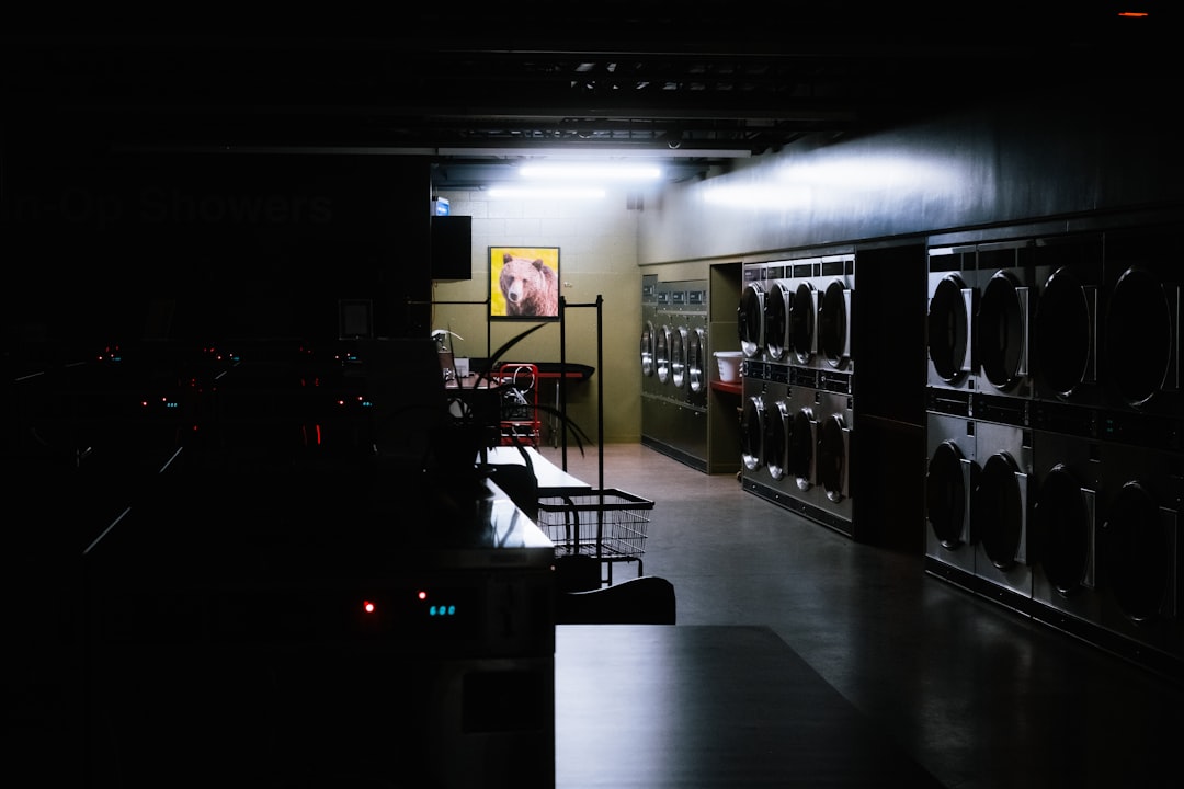 Empty coin-operated laundromat at night with stacked dryers and vintage signage — the pre-modernization baseline before card conversion