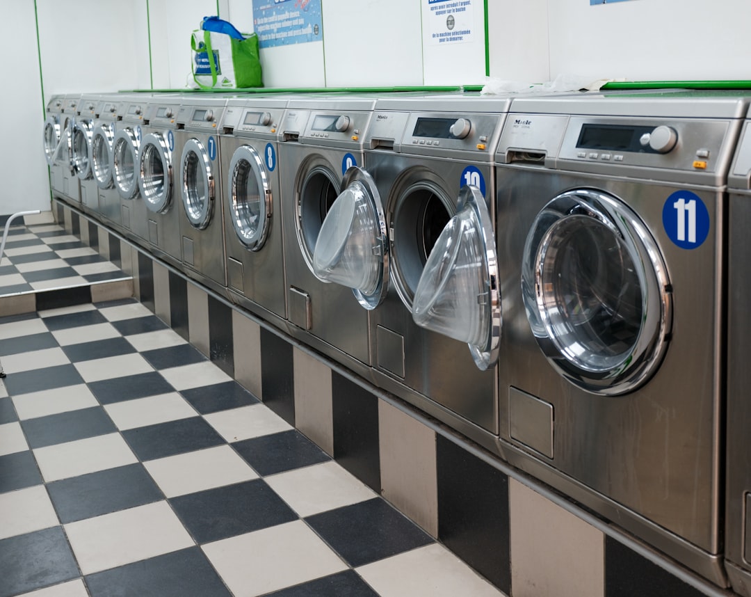 Row of numbered commercial front-load washers along a black-and-white checkered laundromat floor