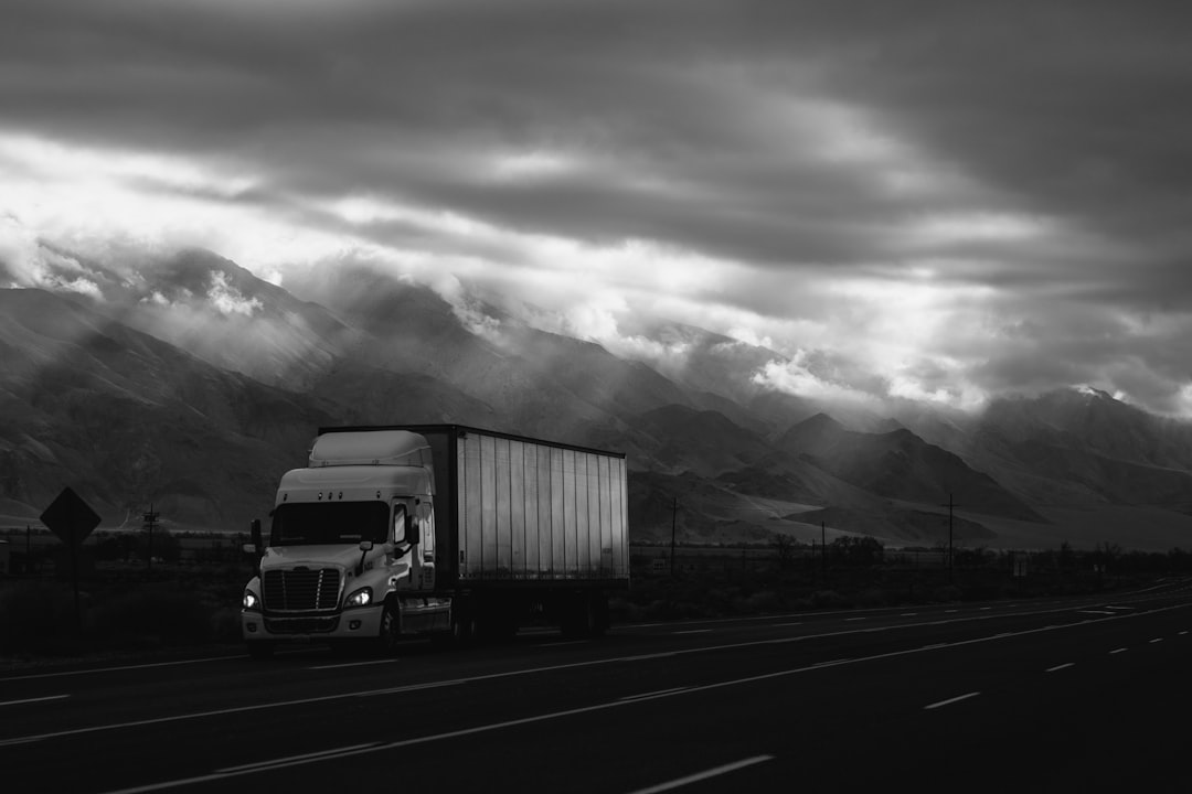 Class 8 semi-truck on an open highway with a dramatic mountain backdrop shot in moody monochrome