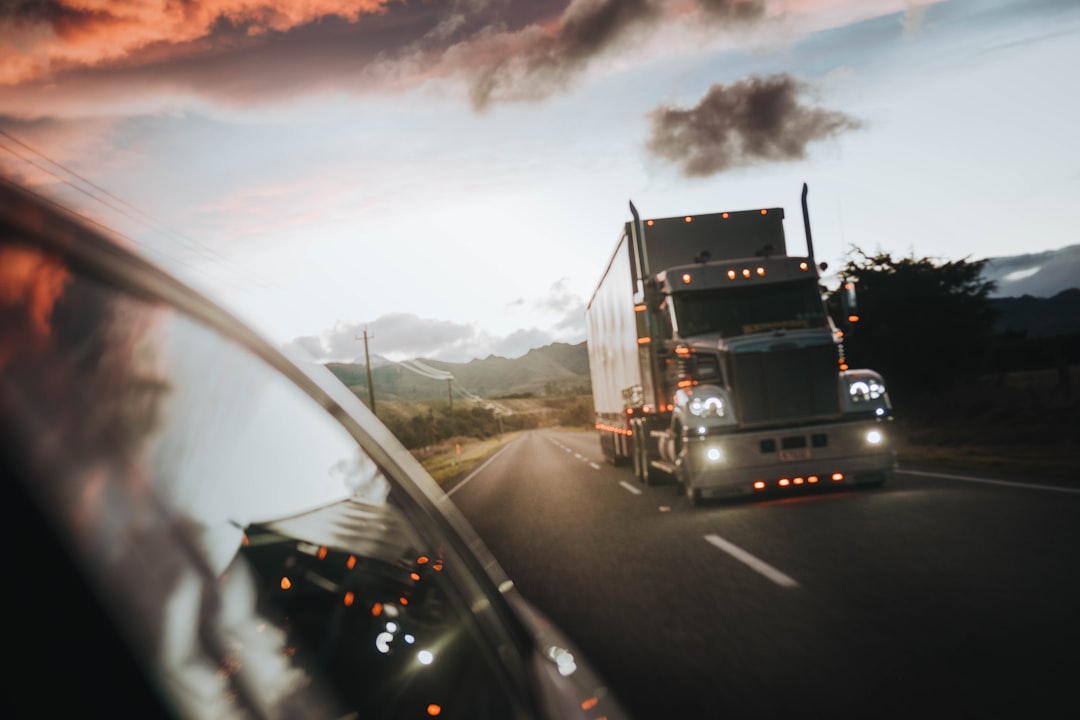 A semi-truck driving down a highway at sunset